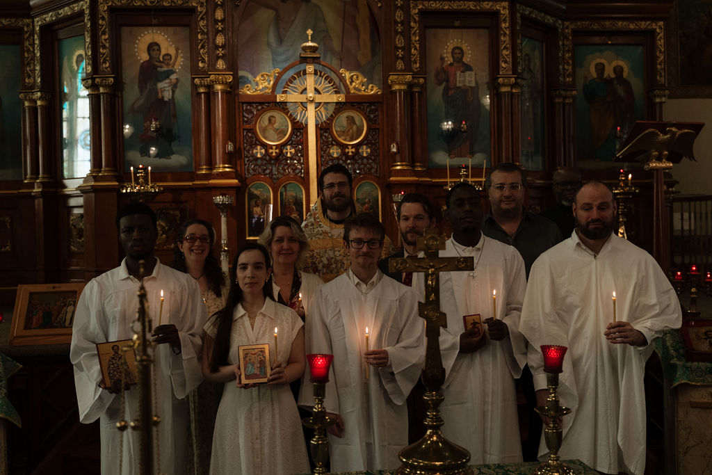 Newly illumined faithful holding candles before the iconostasis